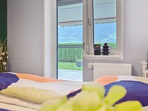 Ein Schlafzimmer mit einem Bett, einem Fenster mit Gartenblick und einer Heizung.