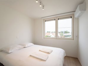 A bedroom with a single bed, two pillows, and two folded towels. There is a window with a view of buildings outside. - Stunning private villa for 6 guests with A/C, WIFI, TV and terrace (Bruges)