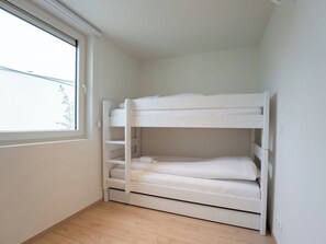 Ein Stockbett in einem Zimmer mit Fenster und Holzboden.