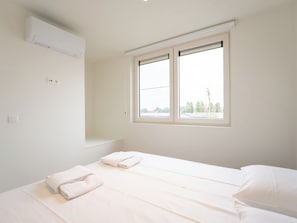Quarto com duas camas, janela e ar condicionado.