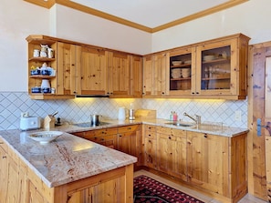 Eine Küche mit Holzschränken, einer Marmorarbeitsplatte und einer gefliesten Rückwand.