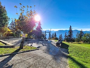 A park with a playground, a stone bench, and a view of mountains. - Nice apartment for 6 people with WIFI, TV, terrace, pets allowed and panoramic view (Crans-montana)