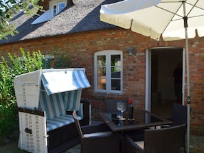 A brick house with a patio area featuring a table, chairs, a wicker sofa, and an umbrella. - Holiday Apartment With 1 Bedroom (Wrixum)