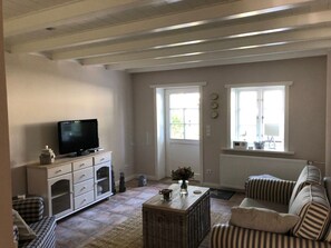 Un saló amb televisió, un sofà, una taula de centre i una finestra amb cortines.