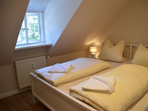 Une chambre avec deux lits, une fenêtre, un radiateur et une lampe de chevet.