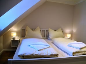 A twin room with two beds, each with a nightstand and lamp, in a sloped ceiling room. - Holiday Apartment With 1 Bedroom (Wrixum)