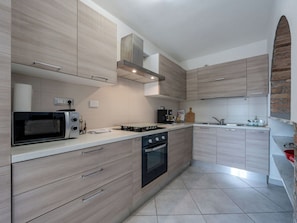 A modern kitchen with light wood cabinetry, a built-in oven, a microwave, and a gas stove. - Cosy apartment for 4 guests with WIFI, A/C, TV and patio (Neive-borgonovo)