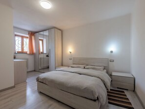 Een slaapkamer met een bed, nachtkastjes, een kledingkast en een raam met gordijnen.