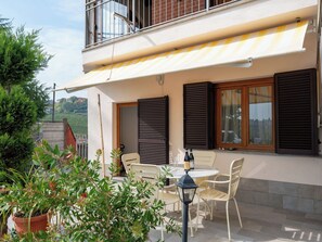 Ein zweistöckiges Gebäude mit Balkon, Außenbereich mit Sitzgelegenheiten und Topfpflanzen.
