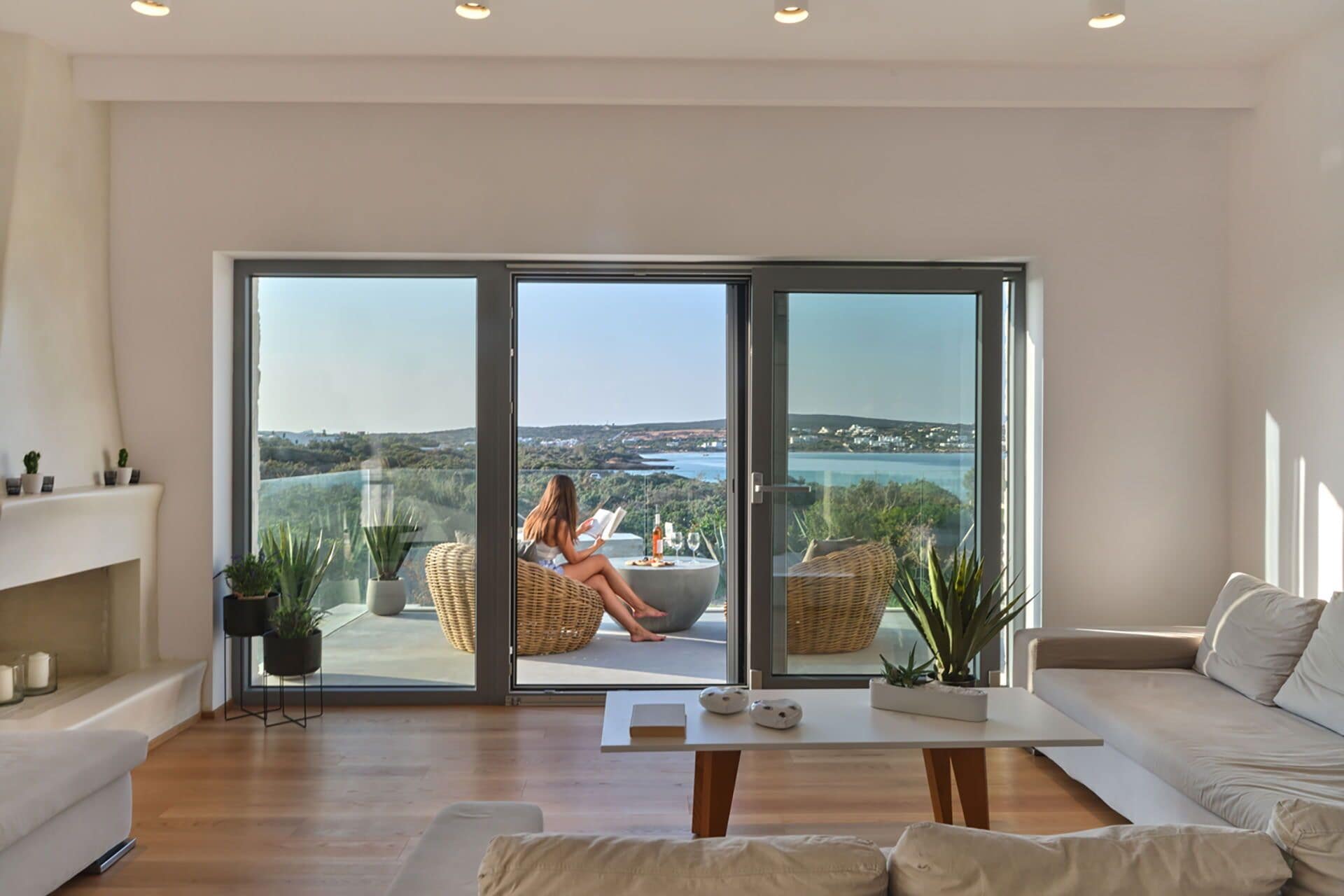 A spacious living room with a large sliding glass door leading to a balcony with a scenic view.
