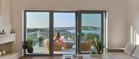 A spacious living room with a large sliding glass door leading to a balcony with a scenic view.