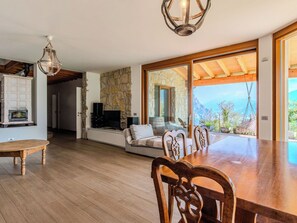 A spacious living area with a stone wall, a fireplace, and a large sliding glass door leading to a balcony with a mountain view.