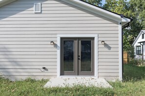 A house with a front door, two exterior wall-mounted lights, a window, and a small overhang above the door. - New 3BR Indianapolis Home  Garage + Laundry (Indianapolis)