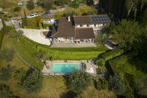 Vista aérea de una propiedad con piscina, paneles solares y un patio cubierto.