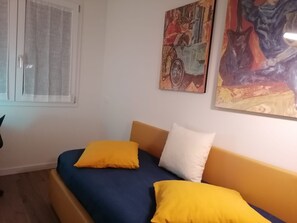 A bed with blue and yellow bedding, a window with curtains, and two paintings on the wall. - ADRY LIVING ART - A Curated Stay in Palermo (Palermo)