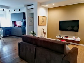 A modern living room with a sofa, a flat-screen TV, and a kitchen in the background. - ADRY LIVING ART - A Curated Stay in Palermo (Palermo)