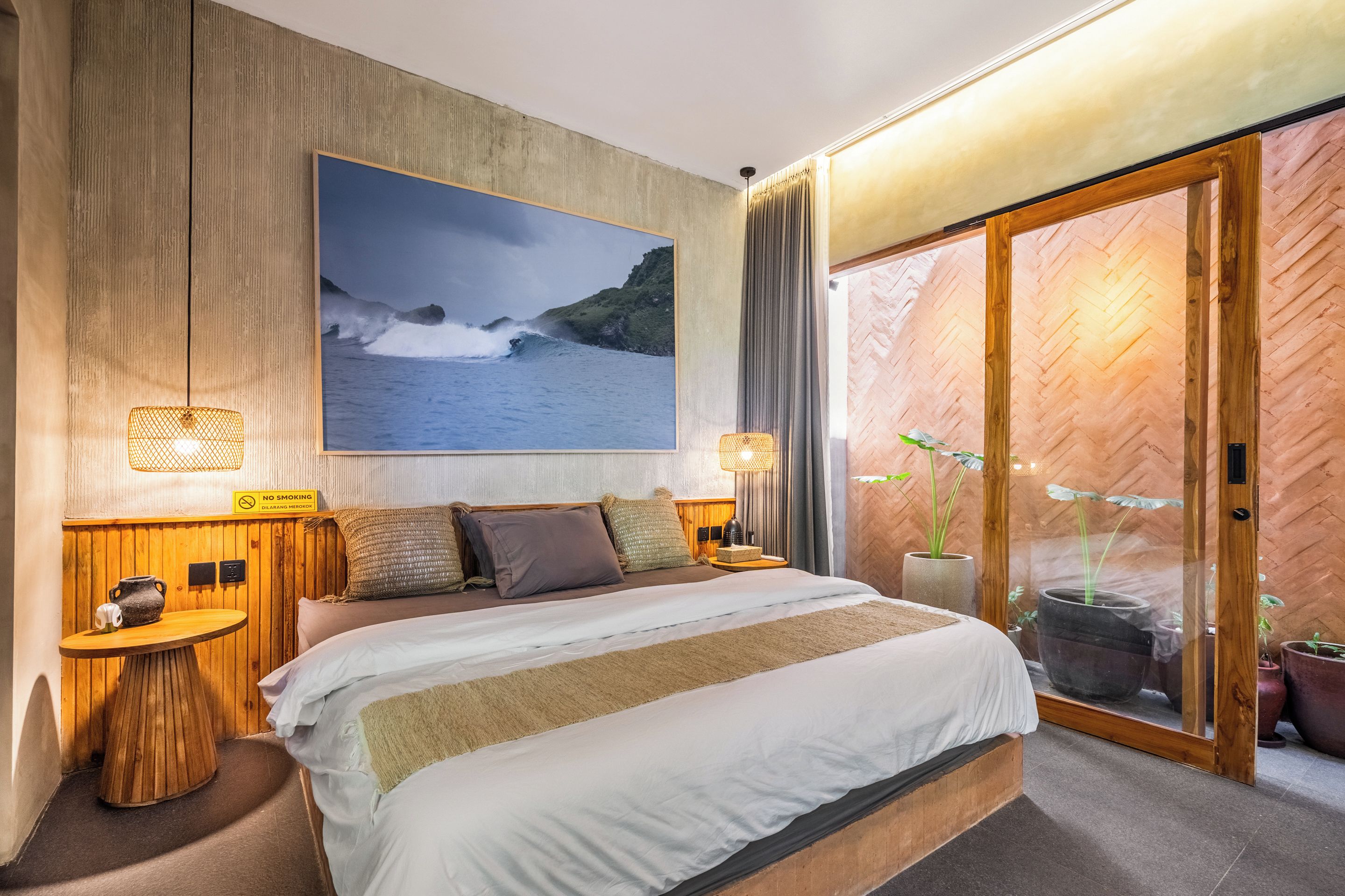Un dormitorio con una cama grande, vista al océano y puerta corrediza de vidrio que da a un espacio exterior.