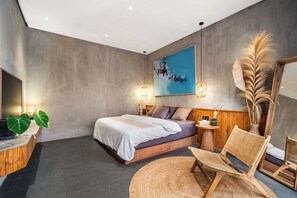 A modern bedroom with a bed, bedside tables, a chair, and a large painting on the wall. - Villa Dinova (Badung)