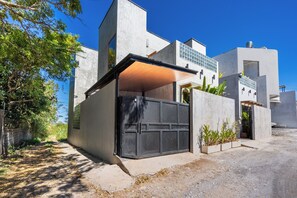 A modern house with a large garage door, a covered porch, and a concrete exterior. - Villa Dinova (Badung)
