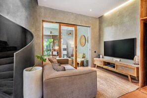 Una sala moderna con un sofá, un televisor de pantalla plana y una escalera.