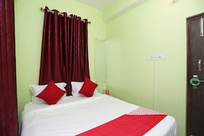 A hotel room with a bed, red curtains, a green wall, and a door with a handle. - Hotel O vibrant inn (Danapur)