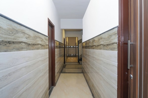 A hallway with marble walls and a wooden door on the right.
