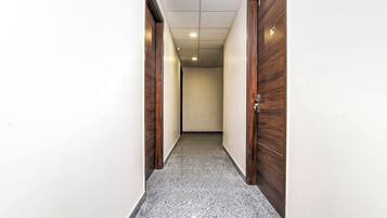 A hallway with wooden doors and a speckled floor.