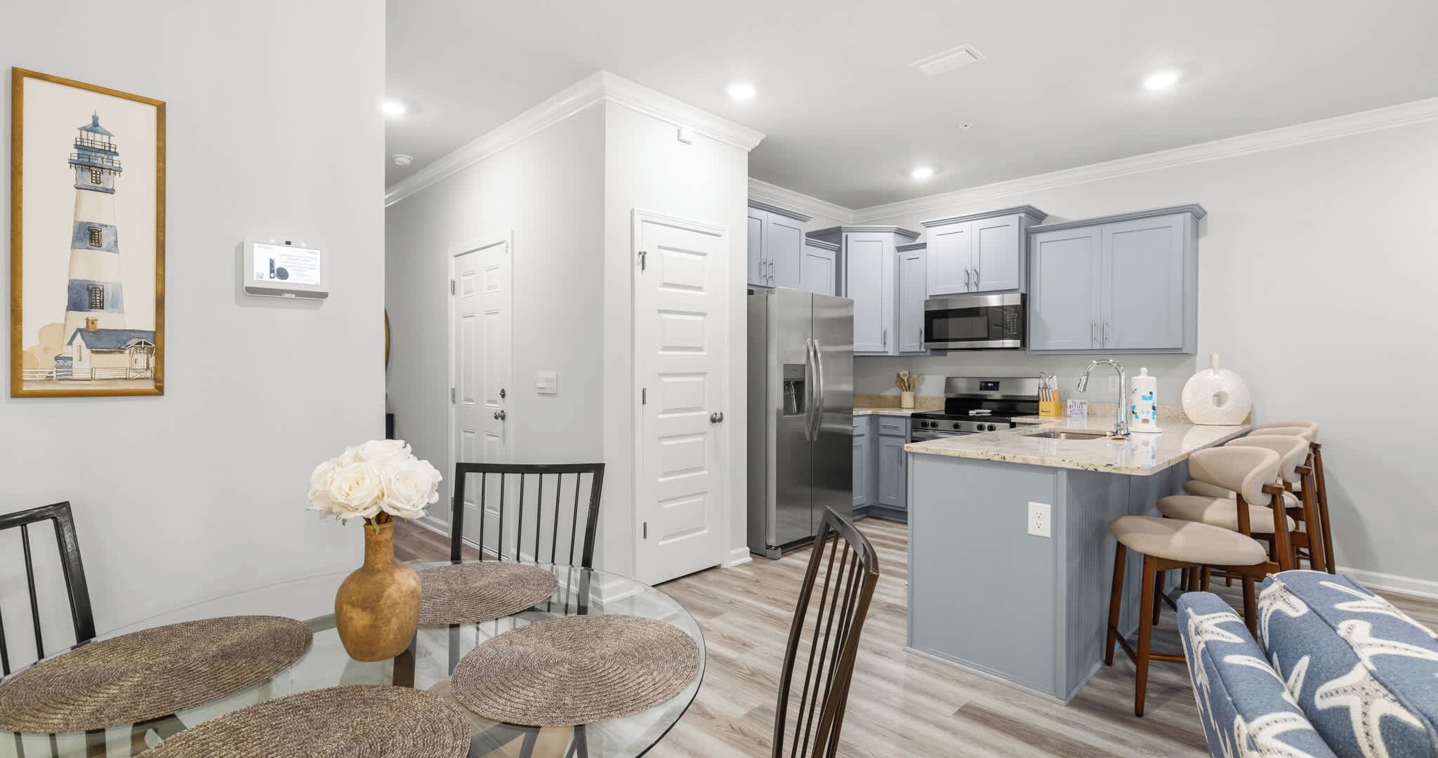 A modern kitchen with a central island, stainless steel appliances, and a dining area with a round table and chairs.