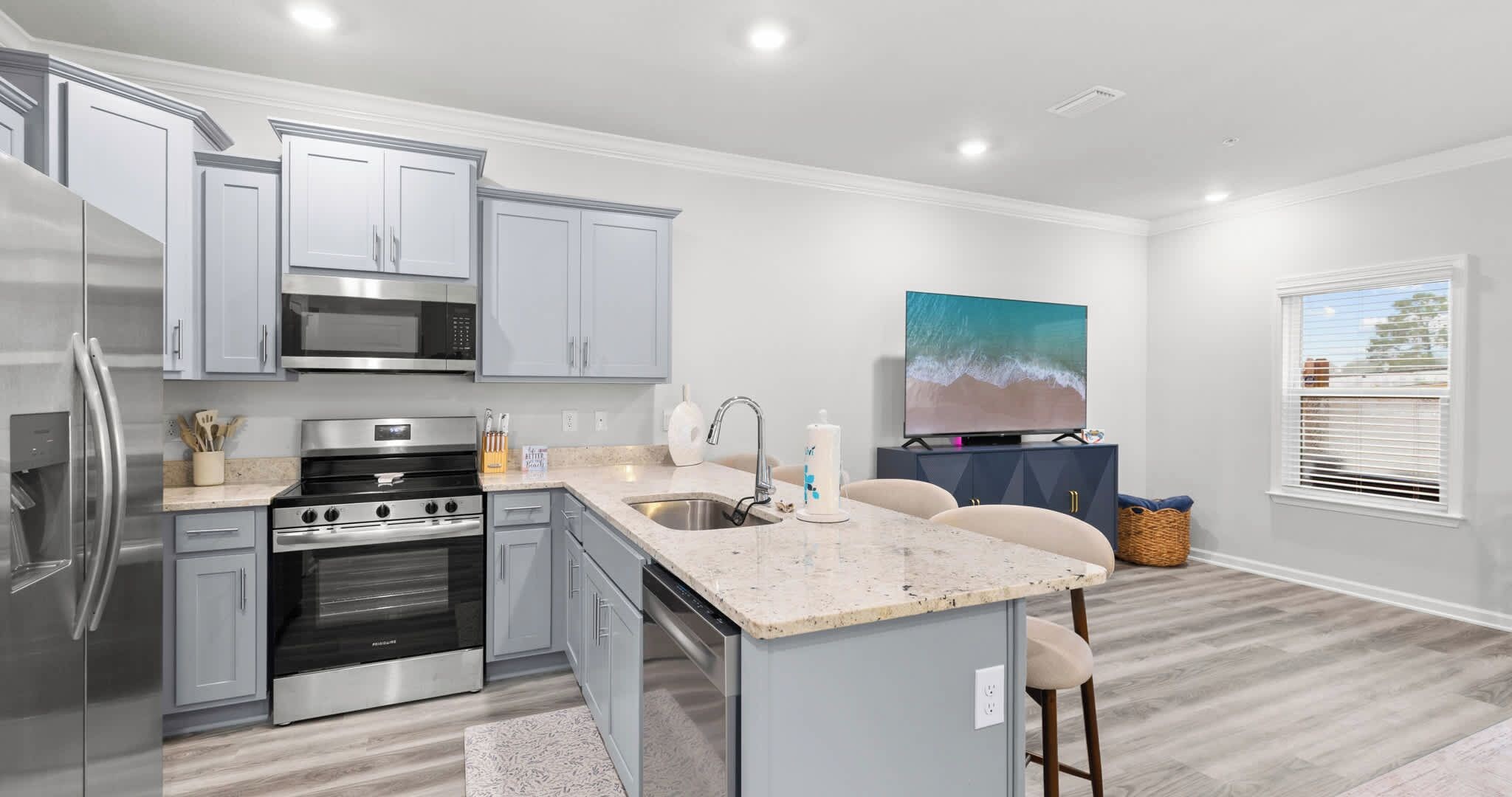 A modern kitchen with stainless steel appliances, a granite countertop, and a large island with bar stools.