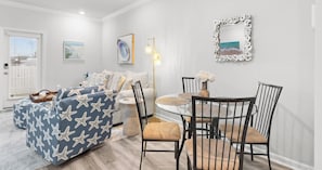 Een woonkamer met een bank, stoelen, een eettafel en kunstwerken aan de muren.