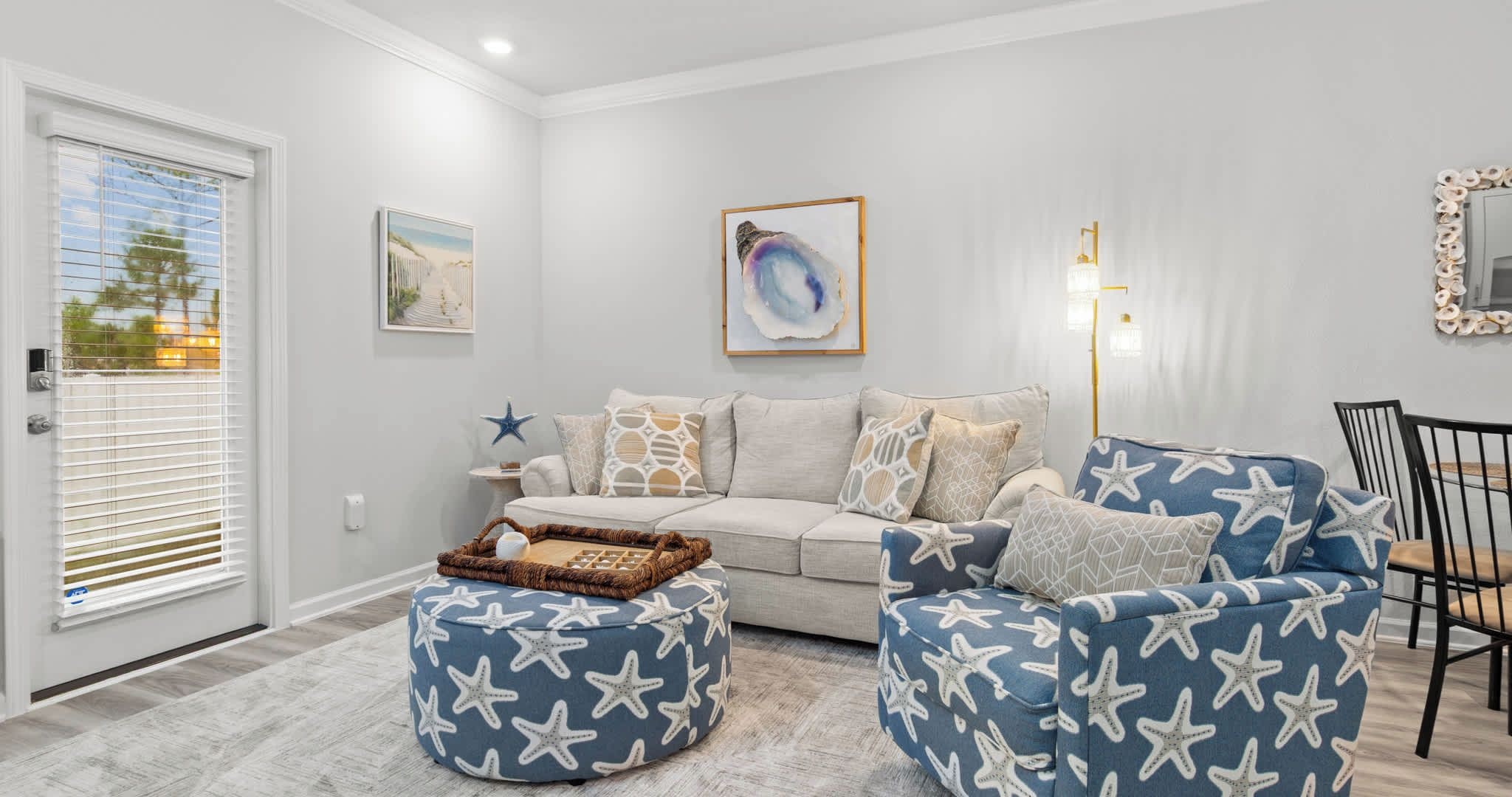 Una sala de estar con un sofá, dos sillones, una mesa de centro y un estampado decorativo de estrella de mar.