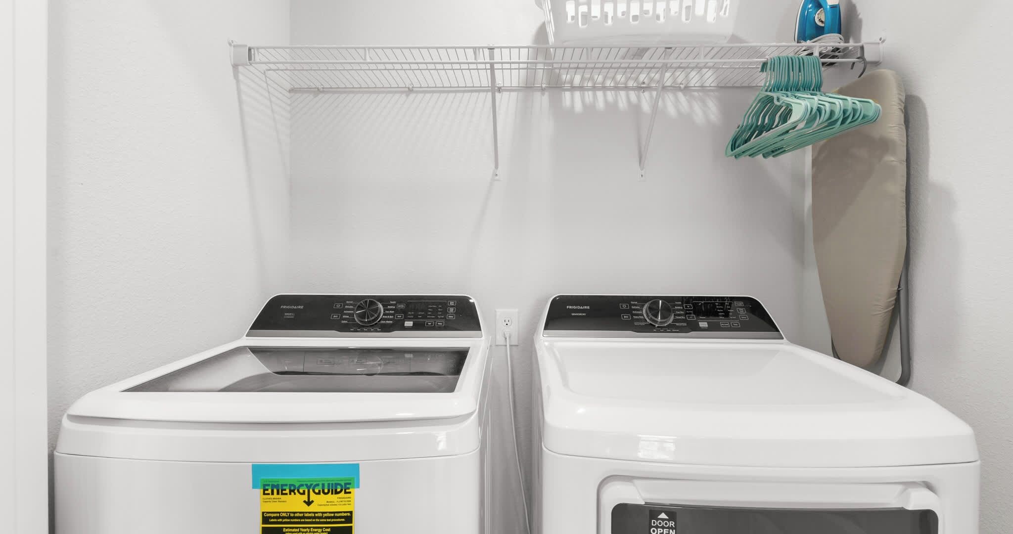 A laundry area with two front-loading washing machines and a drying rack with clothes.