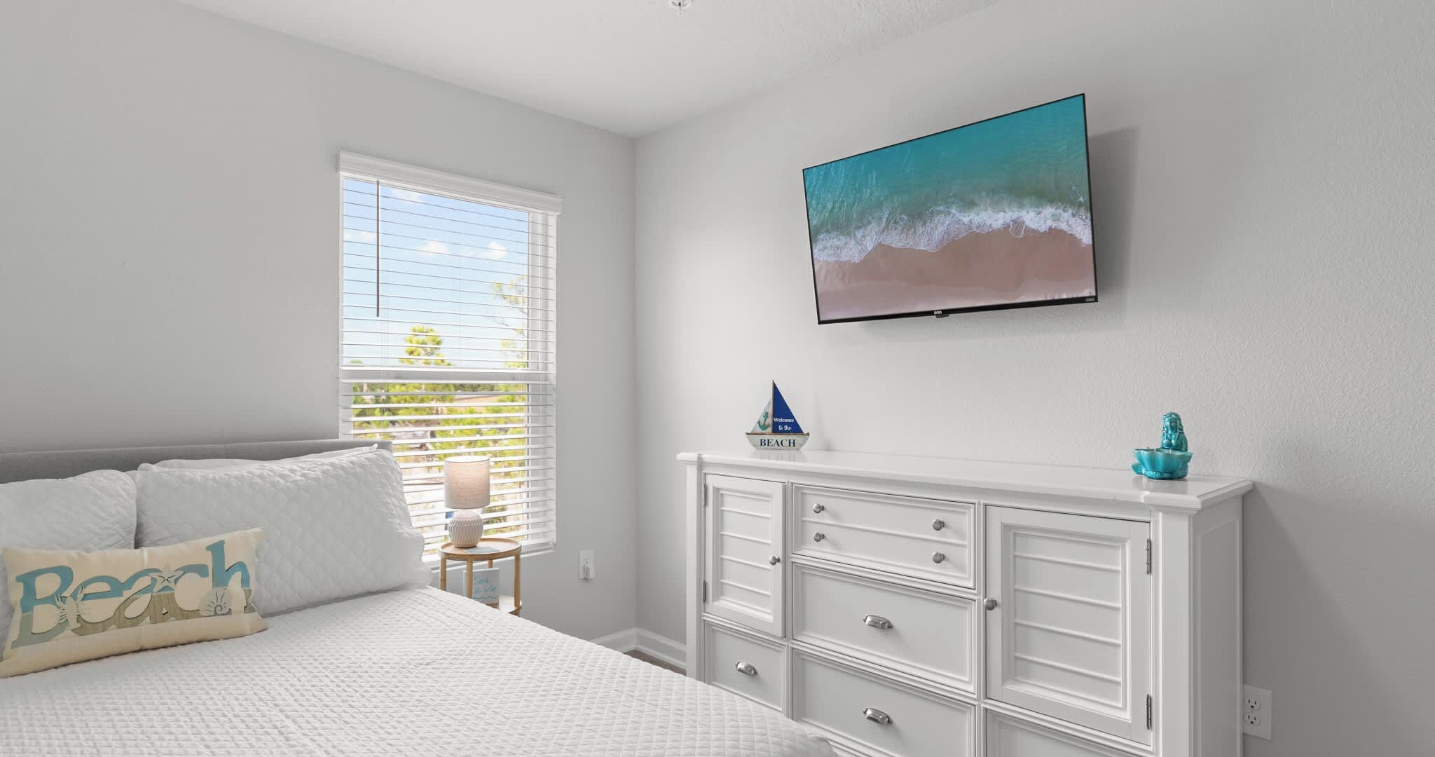 A bedroom with a bed, a dresser, a window with blinds, and a wall-mounted painting.