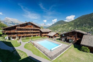 Eine Berghütte mit Pool, Holzbalkonen und Blick auf die umliegenden Berge.