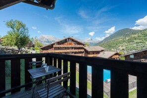 A wooden deck with a table and chairs, overlooking a mountain landscape and a pool. - Geret - Duplex for 6 People | Fireplace | Near the Slopes | Views (Saint-Gervais-les-Bains)