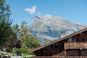 Un chalet de montagne avec une façade en bois, un balcon et une vue sur un imposant sommet.