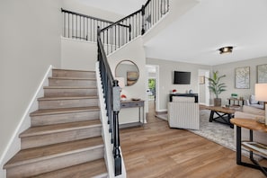 A staircase with wooden steps and black railings leading to a landing. - Four-bedroom Blacksburg home near Virginia Tech with mountain views, front and wraparound porches, fire pit, full kitchen, and basement air hockey. Features 2 king beds, twin room, basement bed, and loft twin beds across 3 levels. (Blacksburg)
