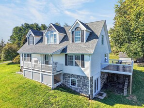 A two-story house with a stone foundation, a balcony, and a covered porch. - Four-bedroom Blacksburg home about 1.6 miles from Virginia Tech with mountain views, front and wraparound porches, fire pit, full kitchen, and basement air hockey. Features 2 king beds, twin room, basement bed, and loft twin beds across 3 levels. (Blacksburg)