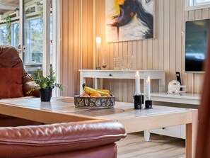 A modern living room with a wooden floor, a sofa, a dining table with fruit and candles, and a TV on the wall. - "Ømunde" - 2.5km from the sea by Interhome (Blokhus)
