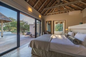 A bedroom with a large bed, a wooden ceiling, and a view of the outdoors. - Villa Acacia: the most exclusive villa in South Africa (Hoedspruit)
