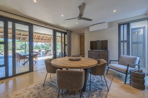 Un espace repas moderne avec une table ronde, six chaises et un ventilateur de plafond.