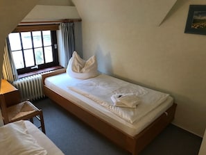 A single bed in a room with a window, a radiator, and a chair. - Hansen Nieblum - Holiday Apartment 2 (Nieblum)