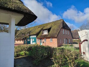 A traditional thatched-roof building with a brick facade, a green door, and a visible number '181'. - Holiday Apartment With 2 Bedrooms (Wrixum)