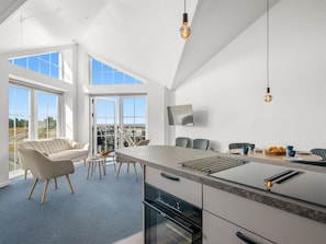 A modern kitchen with a large island, built-in oven, and a dining area with a sofa and chairs. - "Zuhra" - 50m to the fjord by Interhome (Tarm)