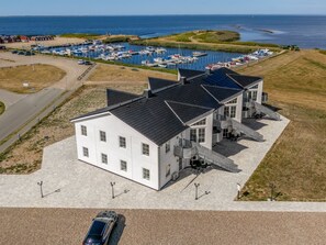 A white building with a flat roof, a covered outdoor area, and a marina in the background. - "Zuhra" - 50m to the fjord by Interhome (Tarm)