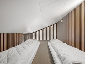 A modern hotel room with two single beds, a sloped ceiling, and wooden paneling on the walls. - "Zuhra" - 50m to the fjord by Interhome (Tarm)