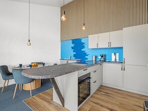 A modern kitchen with a central island, white cabinets, and a blue backsplash. - "Zuhra" - 50m to the fjord by Interhome (Tarm)
