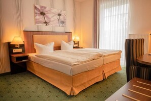 A hotel room with a large bed, two bedside tables with lamps, a chair, and a painting on the wall. - Alte Landratsvilla Hotel Bender GmbH  (Westerburg)