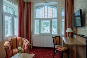 A room with a large window, a television, a lamp, and a chair.