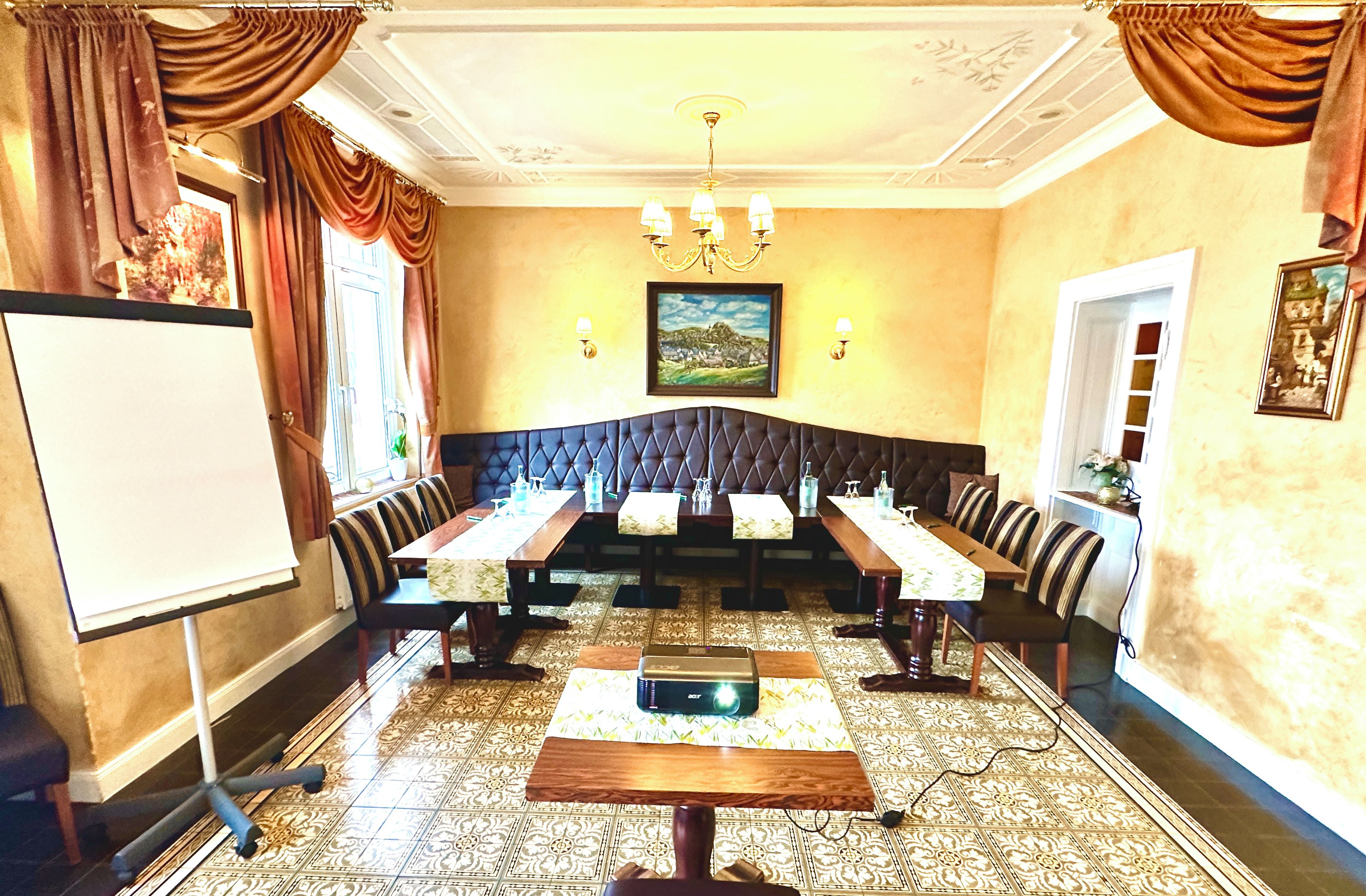 Une salle de conférence avec une longue table, des chaises, un tableau blanc et un lustre.